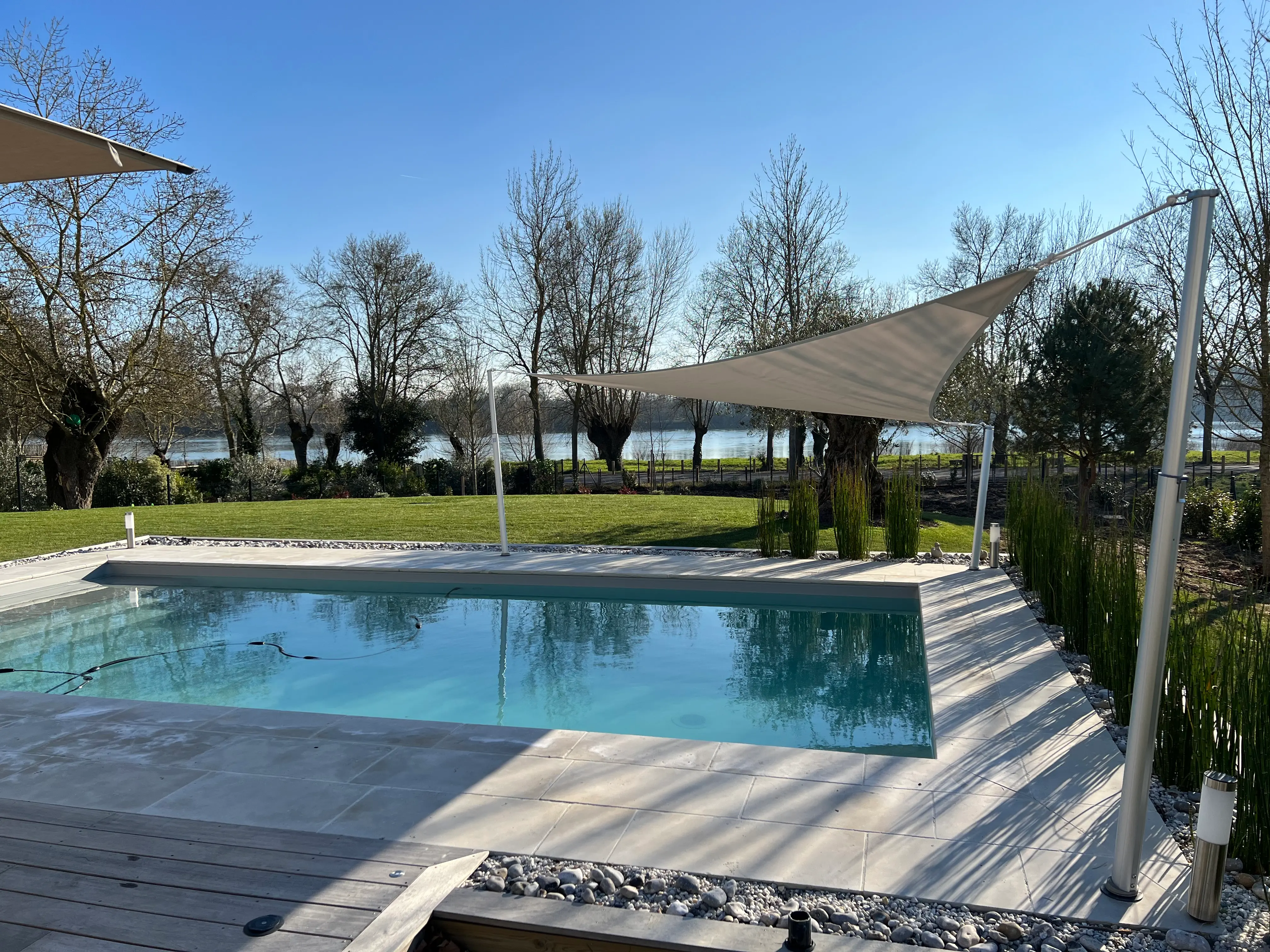 Driehoekig schaduwdoek voor schaduw boven een zwembad met telescopische palen